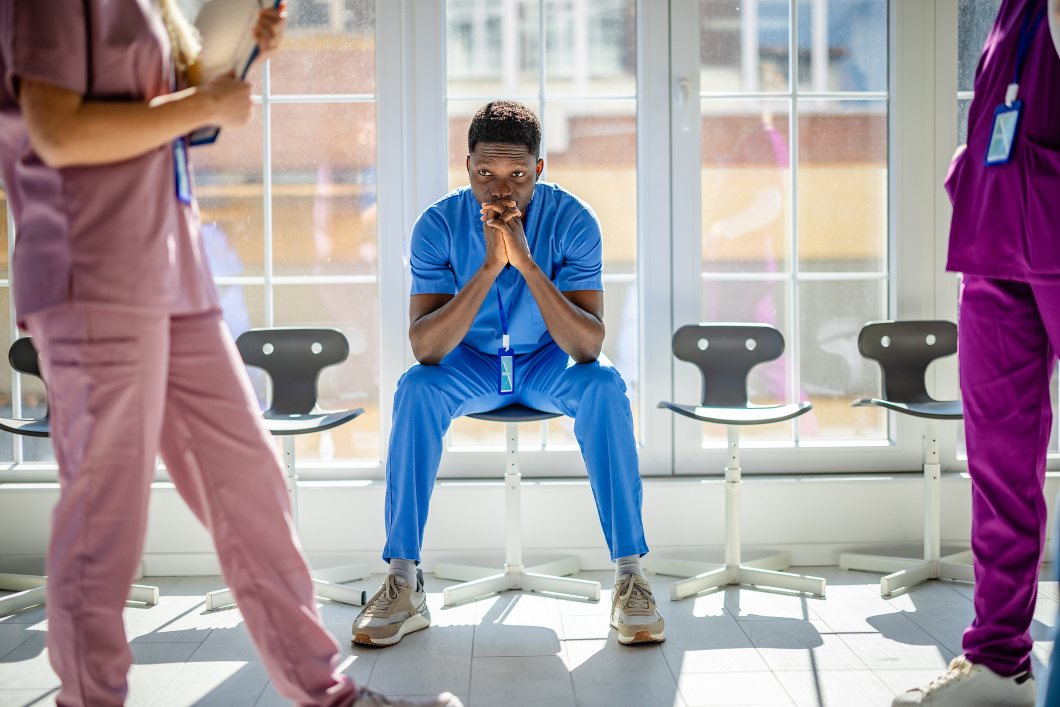 A young healthcare worker sitting in a busy hospital hallway thinking about their values.